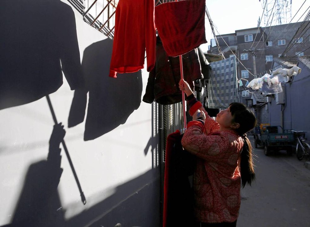 Chi Fan Xinghua (35 tuổi) đang phơi quần áo vào dây phơi ở  phố cổ Bắc Kinh tên Paoju. Ảnh Chicago Tribune